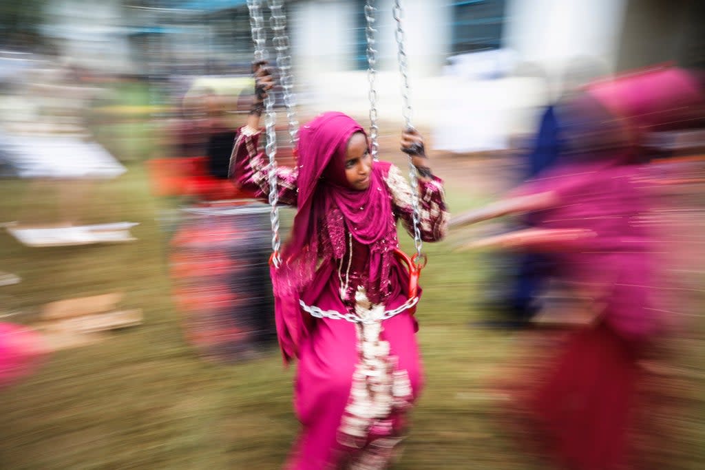 A young Muslim girl enjoys a swing ride during an Eid celebration  (EPA)