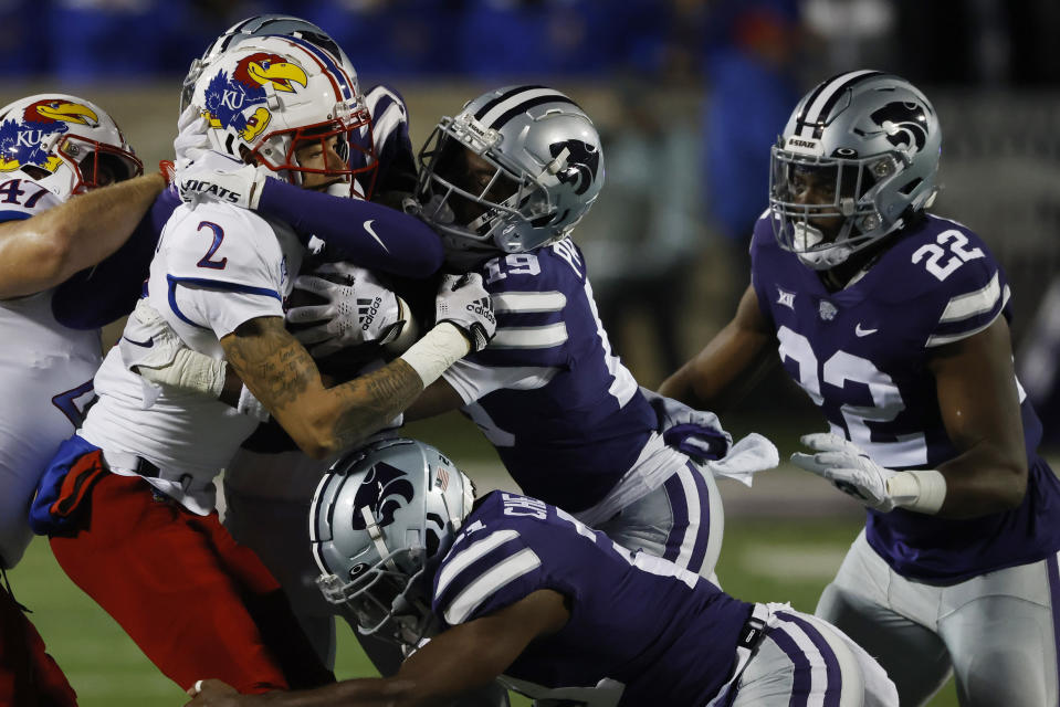 Kansas wide receiver Lawrence Arnold (2) is stopped by Kansas State safety VJ Payne (19), linebacker Daniel Green (22) and safety Drake Cheatum (21) after catching a pass for a first down during the first quarter of an NCAA college football game Saturday, Nov. 26, 2022, in Manhattan, Kan. (AP Photo/Colin E. Braley)