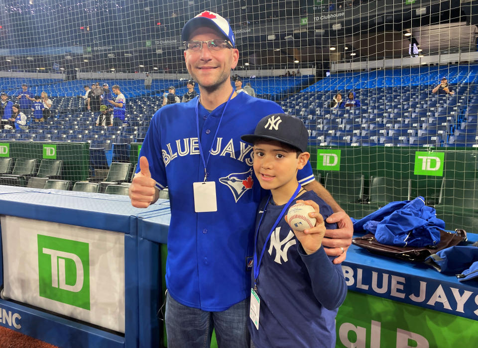 Nine-year-old Derek Rodriguez poses for a photo Wednesday, May 4, 2022, in Toronto with Mike Lanzillotta, the Toronto Blue Jays fan who caught the ball on a home run by New York Yankees' Aaron Judge on Tuesday and handed it to Derek. On Wednesday, Judge signed the ball and met Derek before the game. (Gregory Strong/The Canadian Press via AP)