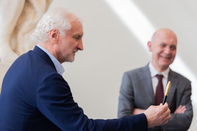 Sports director Rudi Voeller hands over a fountain pen to sign the city's golden book, with DFB president Bernd Neuendorf in the background, during the German national football team's delegation's visit to Duesseldorf ahead of the European Championship. Rolf Vennenbernd/dpa