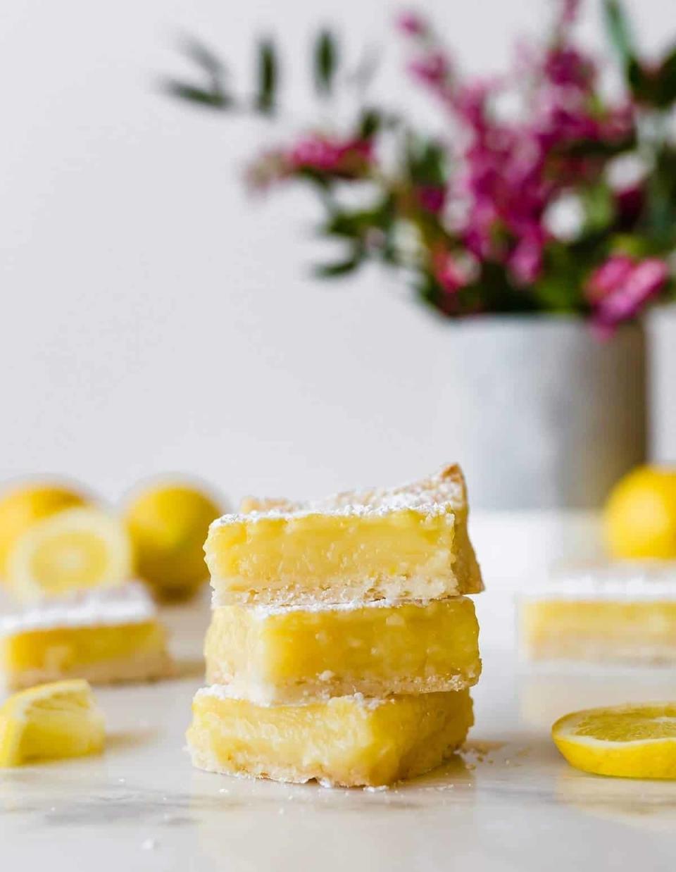 Stack of lemon bars with powdered sugar, fresh lemon slices in the background