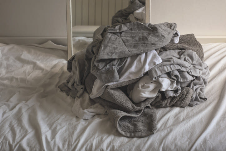 piled sheets and towels on a bed