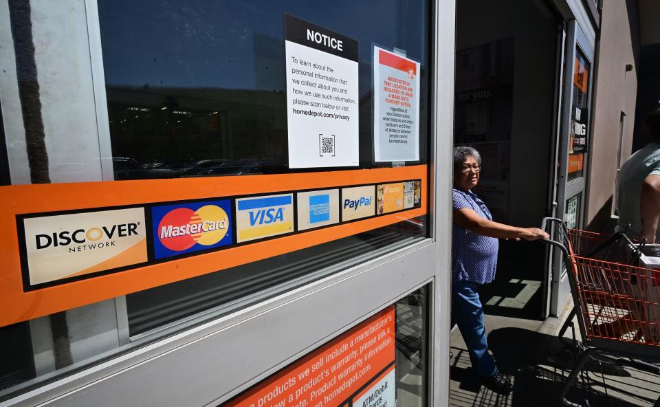 A display of credit cards accepted for use is seen on a door as a shopper steps out of a store on in  Monterey Park, California. (Credit: Frederic J. Brown / AFP)