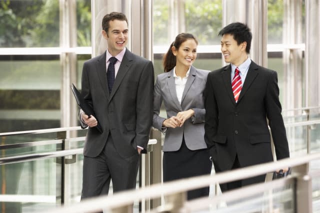 Three Business Colleagues Having Discussion Whilst Walking Outside Office