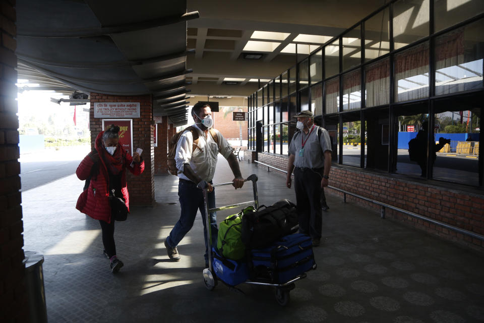 Stranded American citizens arrive to board a Qatar Airways flight at the Tribhuvan International Airport in Kathmandu, Nepal, Tuesday, March 31, 2020. Several American citizens are stranded in Nepal due to the nationwide lockdown enforced in an attempt to stop the coronavirus spread. The new coronavirus causes mild or moderate symptoms for most people, but for some, especially older adults and people with existing health problems, it can cause more severe illness or death. (AP Photo/Niranjan Shrestha)