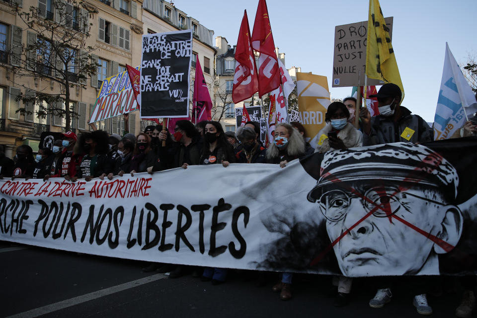 Protester hold a banner reading "For our freedom" and showing a defaced portrait of Paris police prefect Didier Lallement during a demonstration against a security law that would restrict sharing images of police, Saturday, Nov. 28, 2020 in Paris. Thousands of critics of a proposed French security law that would restrict sharing images of police have gathered across the country Saturday in protest. Civil liberties groups and journalists are concerned that the measure will stymie press freedoms and allow police brutality to go undiscovered and unpunished. The cause has gained fresh impetus in recent days after footage emerged of French police officers beating up a Black man, triggering a nationwide outcry. (AP Photo/Francois Mori)