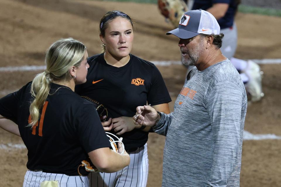 Oklahoma State Head Coach Kenny Gajewski, right, talks with players Ivy Rosenberry, left, and Karli Godwin, center, after an inning in a fall softball game against Seminole State College in Stillwater, Okla. on Tuesday, Oct. 10, 2023.