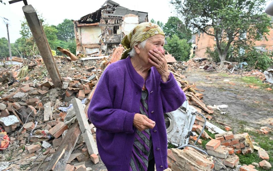 Raisa Kuval, 82, next to a damaged building after a Russian attack on the city of Chuguiv, east of Kharkiv - AFP