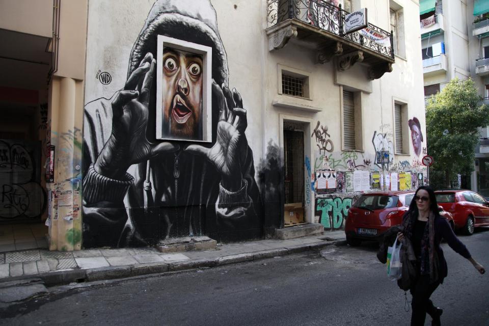 In this photo taken on Thursday Feb. 20, 2014, a woman walks past the work 'capture' by Indonesian-born street artist WD, in the Exarchia area of central Athens. Greece has attracted international street artists to its capital, due to the availability of commissioned work and relatively lax anti-graffiti law. (AP Photo/Dimitri Messinis)