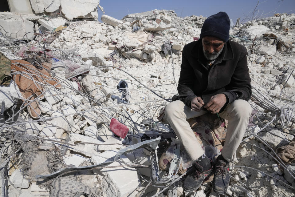 A man sits in the rubble of a destroyed building in Atareb, Syria, Sunday, Feb. 12, 2023. Six days after a massive earthquake killed thousands in Syria and Turkey, sorrow and disbelief are turning to anger and tension over a sense that there has been an ineffective, unfair and disproportionate response to the historic disaster. (AP Photo/Hussein Malla)