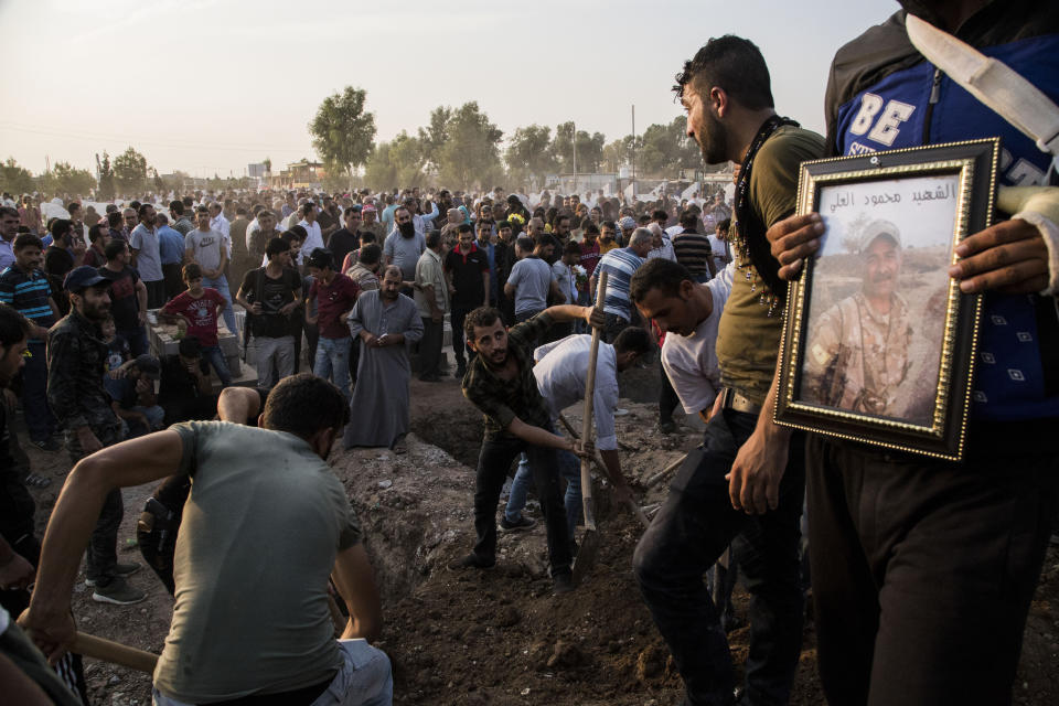 Syrians bury Syrian Democratic Forces fighters killed fighting Turkish advance in the Syrian town of Qamishli, Saturday, Oct. 12, 2019, Turkey's military says it has captured a key Syrian border town Ras al-Ayn under heavy bombardment in its most significant gain as its offensive against Kurdish fighters presses into its fourth day. (AP Photo/Baderkhan Ahmad)