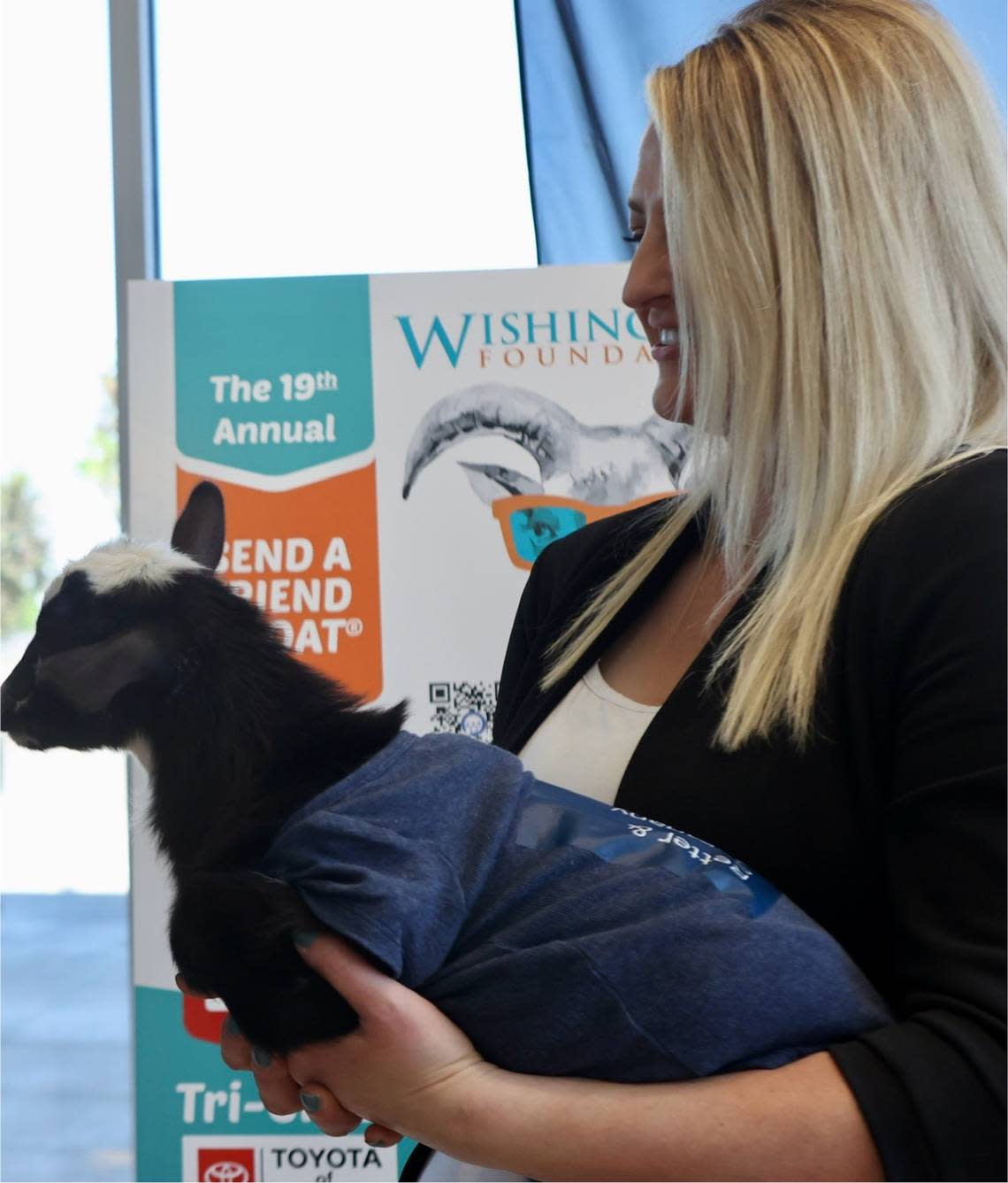 An employee from Toyota of Tri-Cities holdsa baby goat named Taco.