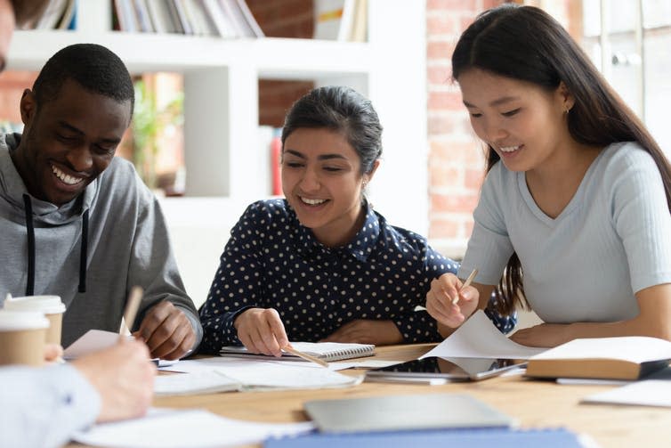 Black, South Asian and East Asian students laughing while studying together