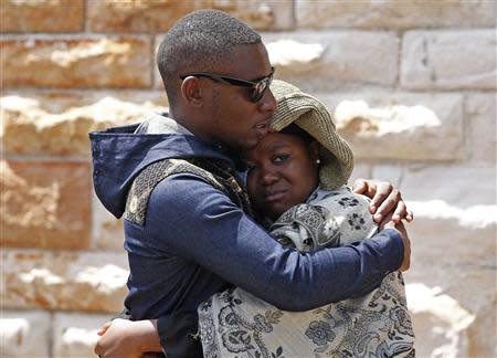 A man and woman comfort each other after paying their respects at the coffin of former South African President Nelson Mandela as Mandela lies in state at the Union Buildings in Pretoria December 11, 2013. REUTERS/Yves Herman