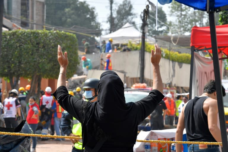 A woman watches as rescue teams search for survivors at a school where an earthquake left at least 21 children dead