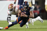 Denver Broncos quarterback Russell Wilson, foreground, is tackled by San Francisco 49ers linebacker Dre Greenlaw during the first half of an NFL football game in Denver, Sunday, Sept. 25, 2022. (AP Photo/David Zalubowski)