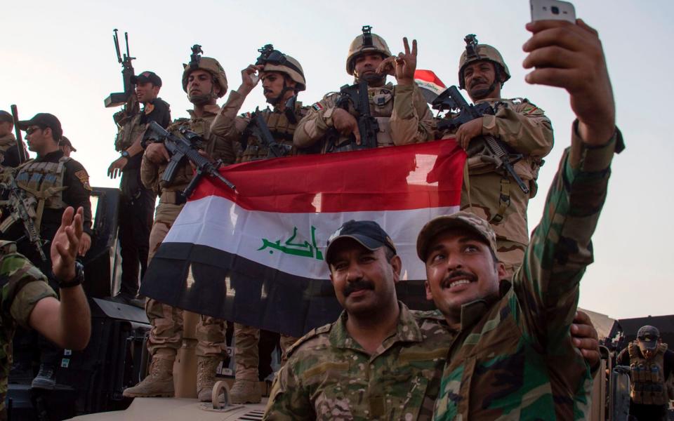 Members of the Iraqi forces celebrate in the Old City of Mosul on July 10, 2017 after the government's announcement of the "liberation" of the embattled city from Islamic State - Credit: AFP