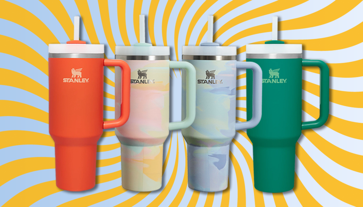 Four different versions of the 40 oz Stanley Quencher sit against a colorful background that's reminiscent of a sky and sunshine.