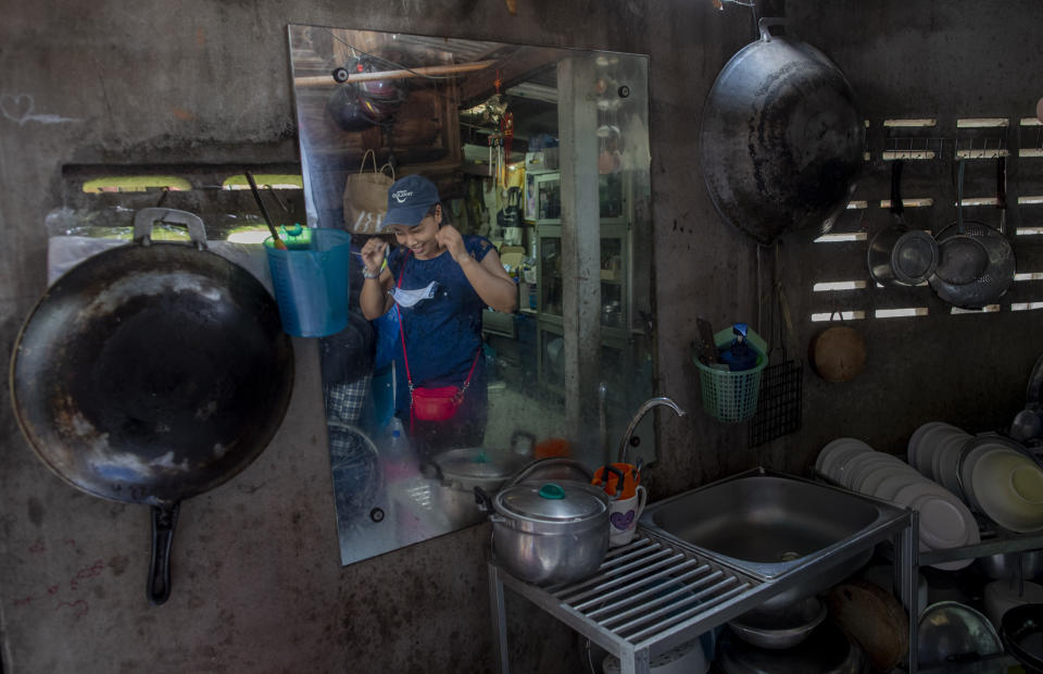 Katsane Sattapitak, cook of Makkasan preschool, is reflected on a mirror in her house as she walks out to distribute meals for children in Bangkok, Thailand, Wednesday, June 24, 2020. Teachers are preparing to welcome students back to school with face masks, mandatory hand washing, and social distancing. Katsane, whose son is a student of the school, says she is confident with the preparations in place to prevent the spread of COVID-19 when the schools restart on July 1. (AP Photo/Gemunu Amarasinghe)