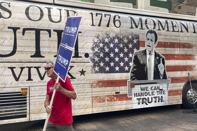 A supporter of former President Donald Trump walks past the campaign bus of candidate Vivek Ramaswamy outside Fiserv Forum in Milwaukee on Tuesday ahead of the first Republican presidential primary debate on Wednesday. Photo by Tannen Maury/UPI