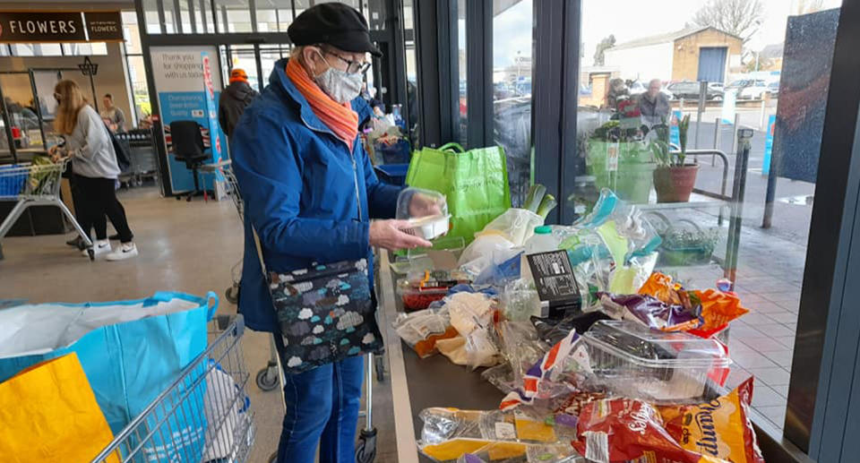 A woman unwrapping groceries in ALDI to show the amount of plastic used.