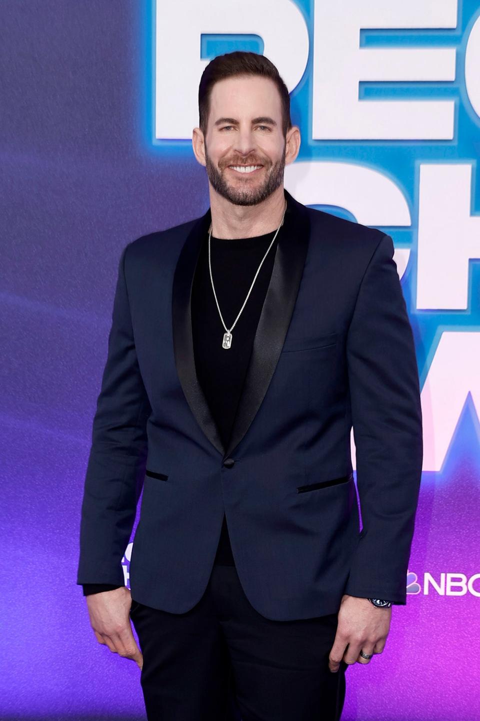 Tarek El Moussa smiling and wearing a dark suit