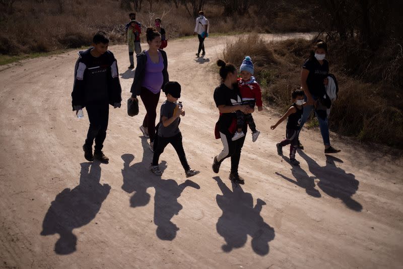 Migrant families walk down dirt road after crossing the Rio Grande River into thr U.S. from Mexico in Penitas, Texas