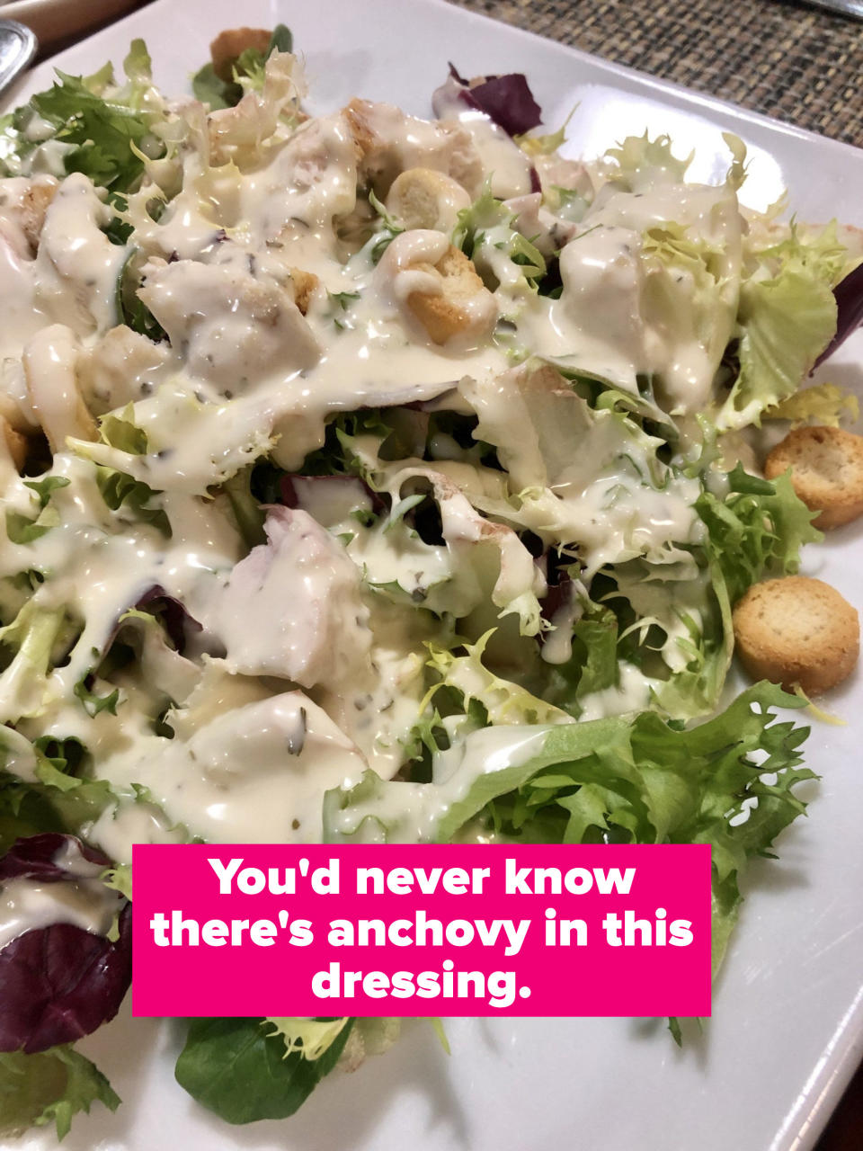 A Caesar salad with dressing on a plate.