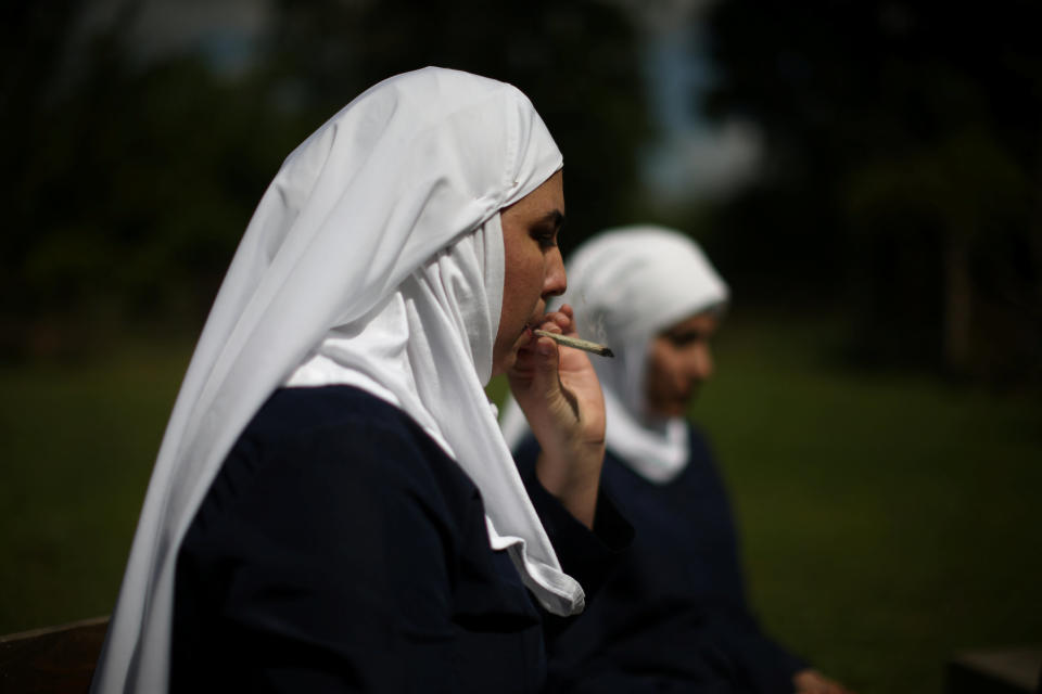 California "weed nun" Desiree Calderon, who goes by the name Sister Freya (L), and India Delgado, who goes by the name Sister Eevee, smoke a joint at Sisters of the Valley near Merced, California, U.S., April 18, 2017. Picture taken April 18, 2017. REUTERS/Lucy Nicholson