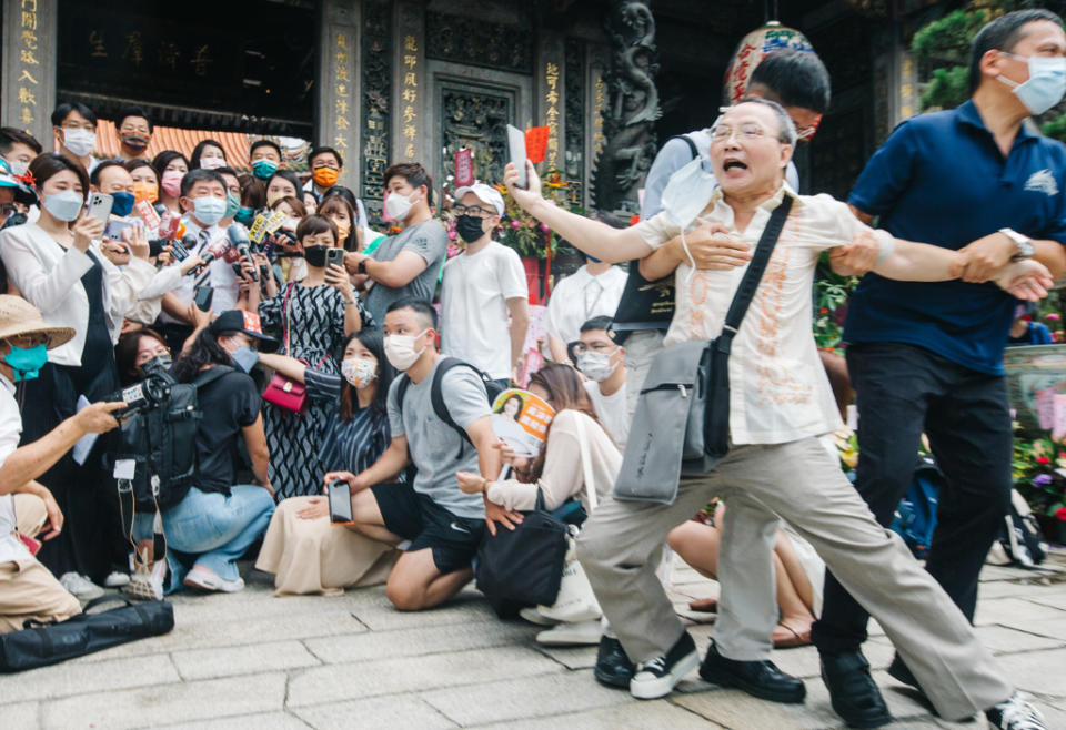 台北市長參選人陳時中20日前往龍山寺參拜，有民眾（右）大喊「陳時中可以保障台北市民嗎」，隨即遭維安人員架離現場。（郭吉銓攝）