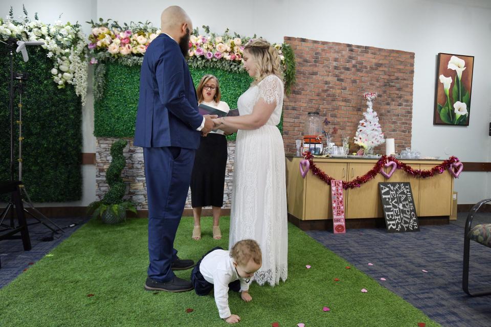 Mike Estronza and Kelsey Murphy say their wedding vows as 13-month old son Julius crawls between them while notary Sonia De Los Santos performs their wedding ceremony at the Rainbow Wedding Chapel on Valentine's Day. Theirs was one of 10 weddings conducted at the chapel next to the Duval County Courthouse.