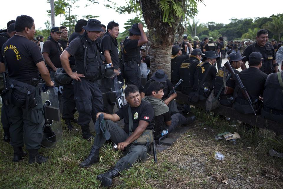 Riot police rest before the start of an operation against illegal mining in Peru's Madre de Dios region in Peru, Monday, April 28, 2014. Some 1,500 soldiers, police and marines have begun destroying illegal gold mining machinery in Peru’s southeastern jungle region of Madre de Dios. Authorities began enforcing a ban on illegal mining Monday in the Huepetuhe district. They had given the state’s illegal miners until April 19 to get legal or halt operations. (AP Photo/Rodrigo Abd)