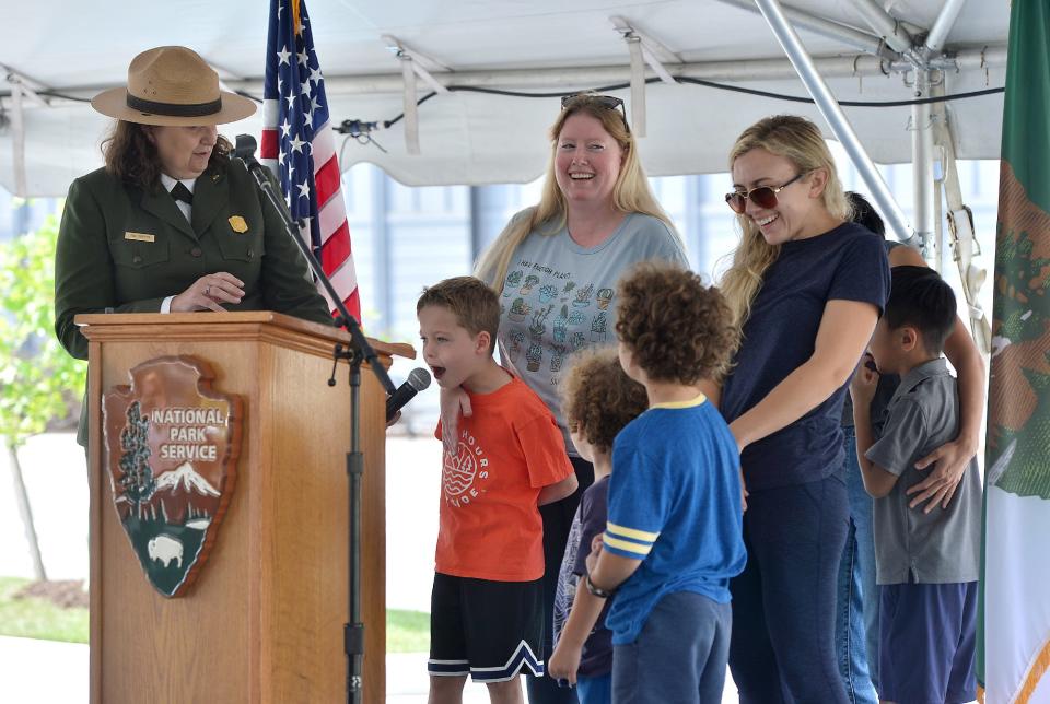 Tina Cappetta, left, superintendent of the Chesapeake and Ohio Canal National Historic Park, holds a microphone for John Hoffman, 8, standing with his mother Karen Hoffman, of Ashburn, Va., as he announces Paw Paw as the name for the mule statue on the grounds of the new C&O Canal headquarters in Williamsport during a ribbon cutting ceremony Wednesday.