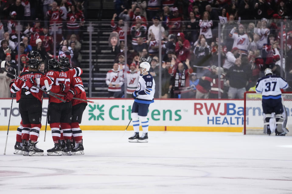 The New Jersey Devils celebrate a goal by Fabian Zetterlund against Winnipeg Jets goaltender Connor Hellebuyck, right, during the third period of an NHL hockey game Sunday, Feb. 19, 2023, in Newark, N.J. The Devils won 4-2. (AP Photo/Frank Franklin II)