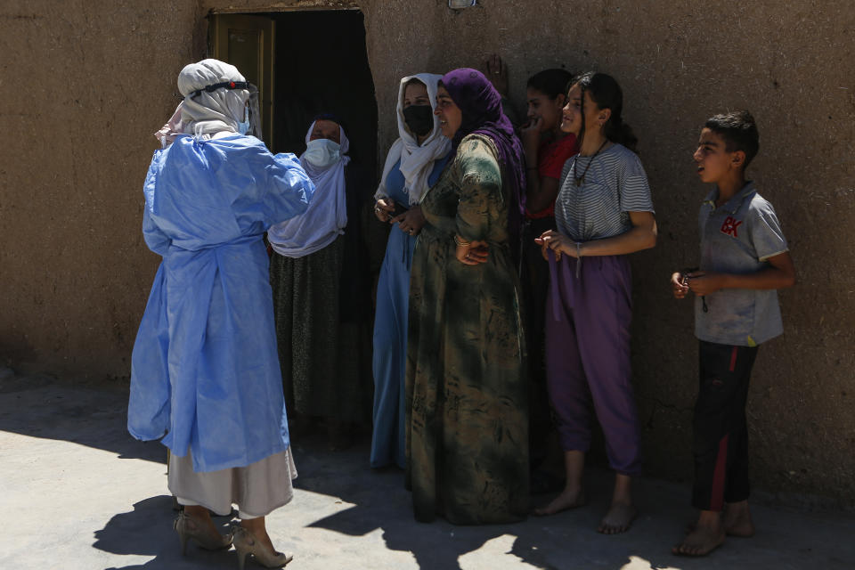 Nurse Meltem Gulcan, left, talks to local residents about the importance of anti COVID-19 vaccination, in the village of Gokce, in the district of Mardin, a culturally and historically diverse region in Turkey's south, overlooking Mesopotamia and bordering Syria, Friday, May 21, 2021. The health worker is part of Turkey's 'vaccination persuasion' teams, a recent initiative that aims to promote inoculation against the coronavirus among the country's most vulnerable population. (AP Photo/Mehmet Guzel)