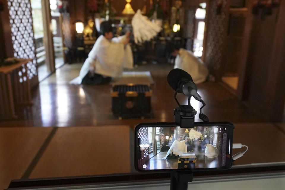 In this May 8, 2020, photo, Ryoki Ono, right, head priest, and another priest perform a livestream prayer during a 10-day trial of "online shrine" visit program at Onoterusaki Shrine in downtown Tokyo, allowing its visitors to join rituals from their homes. The shrine also accepted from worshipers their prayer messages, which were printed on a virtual wooden tablet each and offered to the Shinto gods to keep away evil spirits and the epidemic. (AP Photo/Eugene Hoshiko)