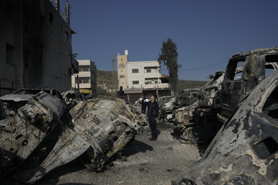 Palestinians take photos of burned cars in the town of Hawara, near the West Bank city of Nablus, Monday, Feb. 27, 2023. Scores of Israeli settlers went on a violent rampage in the northern West Bank, setting cars and homes on fire after two settlers were killed by a Palestinian gunman. Palestinian officials say one man was killed and four others were badly wounded. (AP Photo/Majdi Mohammed)