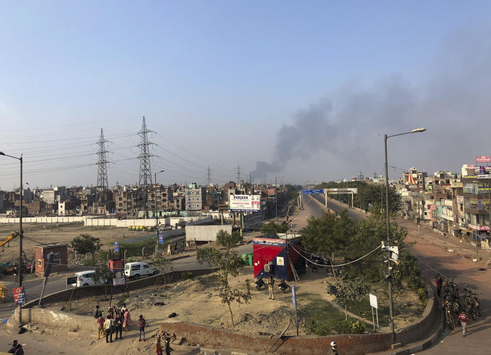 Black smoke rises into the sky after shops are set on fire during violence between two groups in Bhajanpura are of New Delhi, India, Tuesday, Feb. 25, 2020. An angry group of Hindus carrying pickaxes and iron rods hurled rocks at Muslims in new violence in the Indian capital over a new citizenship law on Tuesday, with at least 10 people killed in two days of clashes that cast a shadow over U.S. President Donald Trump's visit to the country. (AP Photo/Sheikh Saaliq)