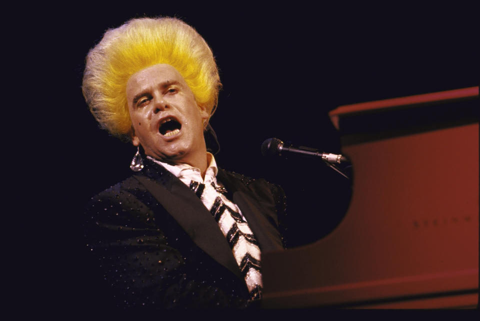 John performs wearing an Amadeus Mozart wig.