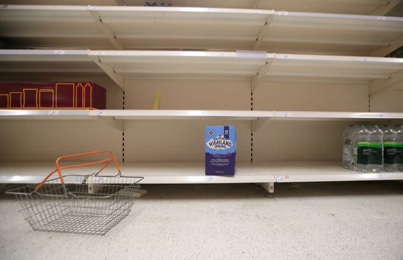 A shopping basket is discarded next to empty shelves of the soft drinks aisle, in Sainsbury's supermarket in Harpenden