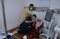 A coronavirus patient receives treatment at a hospital in Najaf, Iraq, Wednesday, July 14, 2021. Infections in Iraq have surged to record highs amid a third wave spurred by the more aggressive delta variant, and long-neglected hospitals suffering the effects of decades of war are overwhelmed with severely ill patients. (AP Photo/Anmar Khalil)