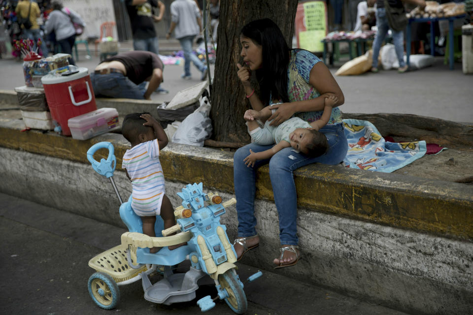 A woman with two children stops prior to crossing the Simon Bolivar International bridge into Colombia, in San Antonio del Tachira, Venezuela, Thursday, Feb. 21, 2019. Opposition leaders led by self-proclaimed interim president Juan Guaido are vowing to bring in U.S. supplies of emergency food and medicine to dramatize the country's hardships under President Nicolas Maduro, who has said the country doesn't need such help. (AP Photo/Rodrigo Abd)