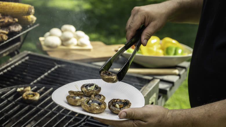 Person pulling mushrooms off of grill