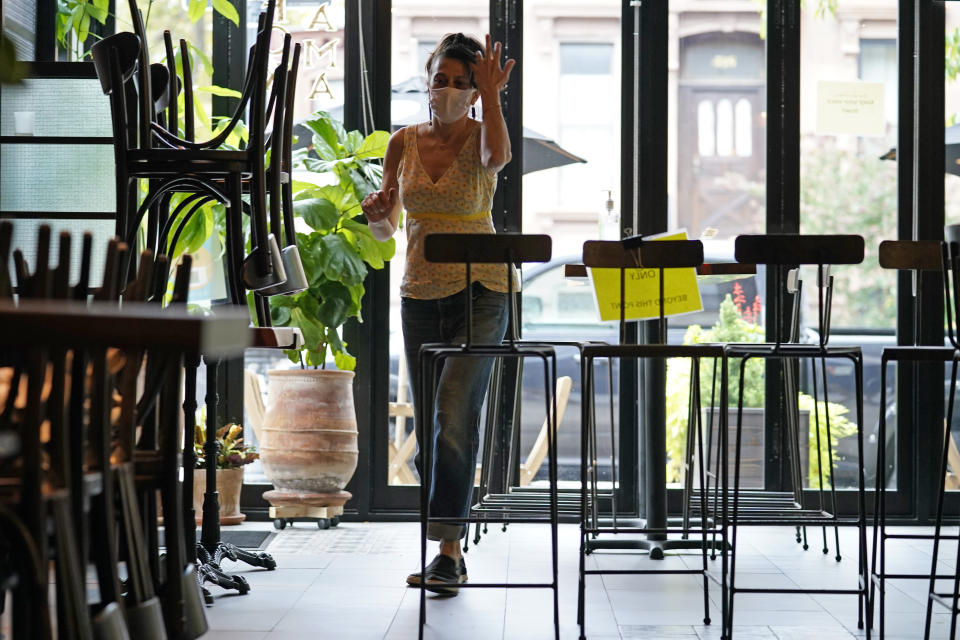 Chairs are still placed atop tables and lined up to form a border as Samantha DiStefano walks through Mama Fox, her Brooklyn restaurant and bar, while preparing for indoor dining, Tuesday, Sept. 29, 2020, in New York. Indoor dining is allowed in the city as of Wednesday, but DiStefano plans to take it slowly at first. (AP Photo/Kathy Willens)