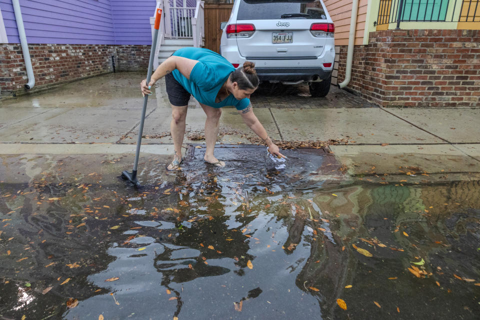 Crystal Hilgado uses a broom to clean out the drain on her street near downtown New Orleans on Wednesday, April 10, 2024. Severe thunderstorms were expected across parts of the Louisiana, Mississippi, Alabama and the Florida panhandle and there was the potential for tornadoes, a few of which may be strong, and damaging winds, which may exceed 75 mph (120 kph), the National Weather Service warned.(Chris Granger /The Times-Picayune/The New Orleans Advocate via AP)