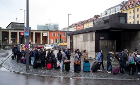 Commuters line up for a bus to the airport in front of a Deutsche Bahn building during a rail workers' strike across the country due to a pay dispute with Deutsche Bahn, in Munich, Germany December 10, 2018. REUTERS/Martin Hangen