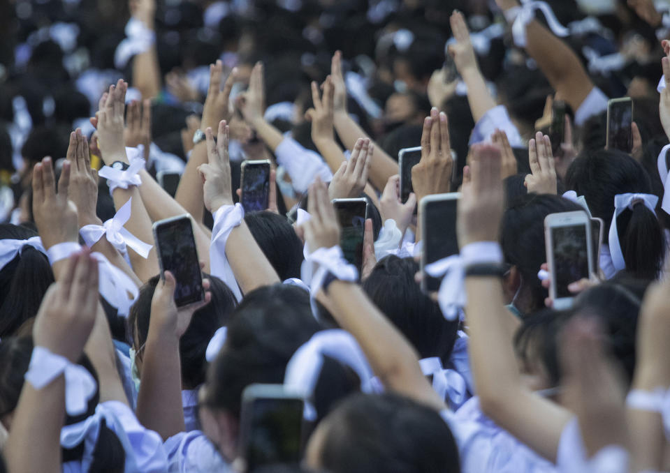 Pro-democracy students raise a three-fingers, symbol of resistance salute and their mobile phone during a protest rally in front of Education Ministry in Bangkok, Thailand, Wednesday, Aug. 19, 2020. Student protesters have stepped up pressure on the government with three core demands: holding new elections, amending the constitution and ending the intimidation of critics of the government. (AP Photo/Sakchai Lalit)