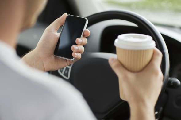 transportation and vehicle concept - man drinking coffee and using phone while driving the car