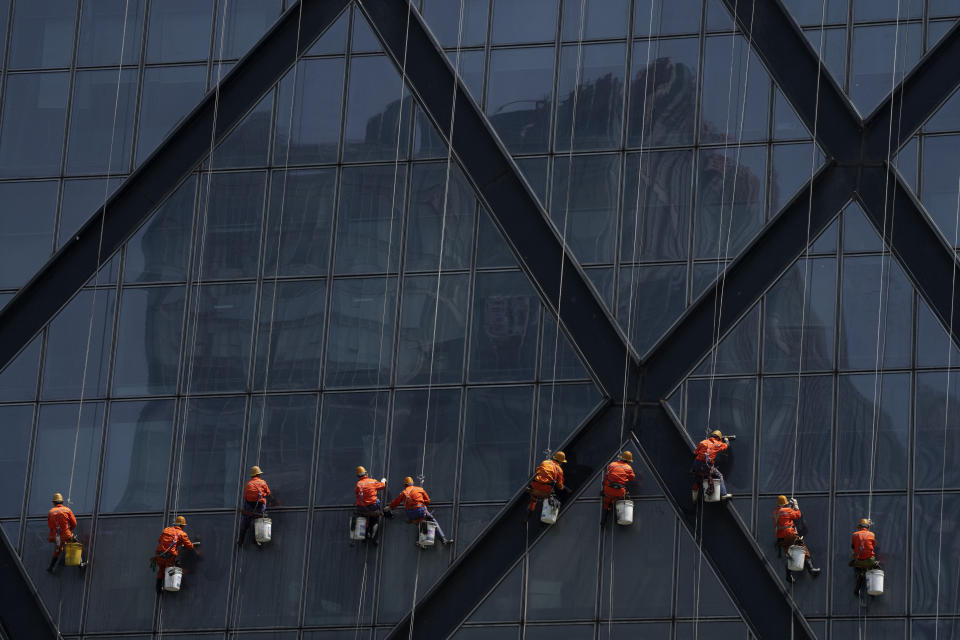 Workers wearing face masks hang from ropes as they wash windows on the China Central Television (CCTV) building in Beijing, Wednesday, May 4, 2022. Beijing on Wednesday closed around 10% of the stations in its vast subway system as an additional measure against the spread of coronavirus. (AP Photo/Mark Schiefelbein)