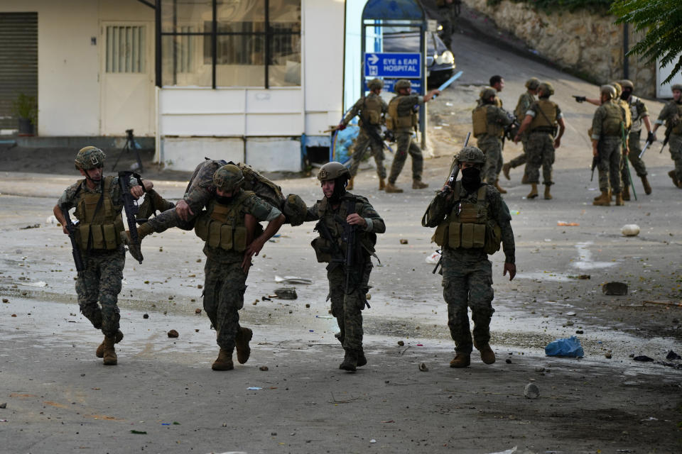 Lebanese army soldiers carry a wounded colleague who was injured during a demonstration, in solidarity with the Palestinian people in Gaza, near the U.S. embassy in Aukar, a northern suburb of Beirut, Lebanon, Wednesday, Oct. 18, 2023. Hundreds of angry protesters are clashing with Lebanese security forces in the Lebanese suburb Aukar near the United States Embassy. (AP Photo/Hassan Ammar)